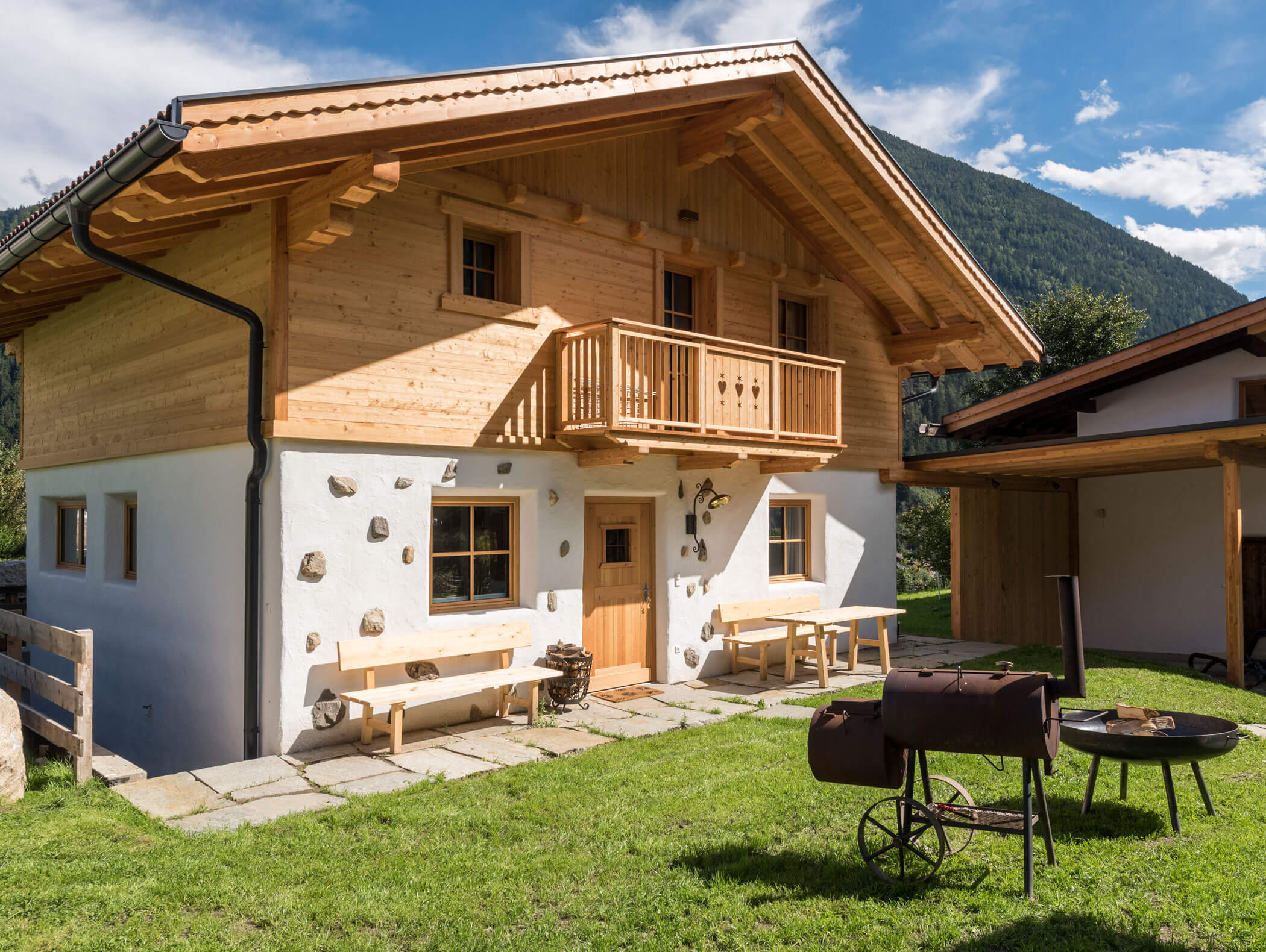 Ein Holzchalet mit Bänken und einem Grill in sonniger Berglage. - Maurlechnhof
