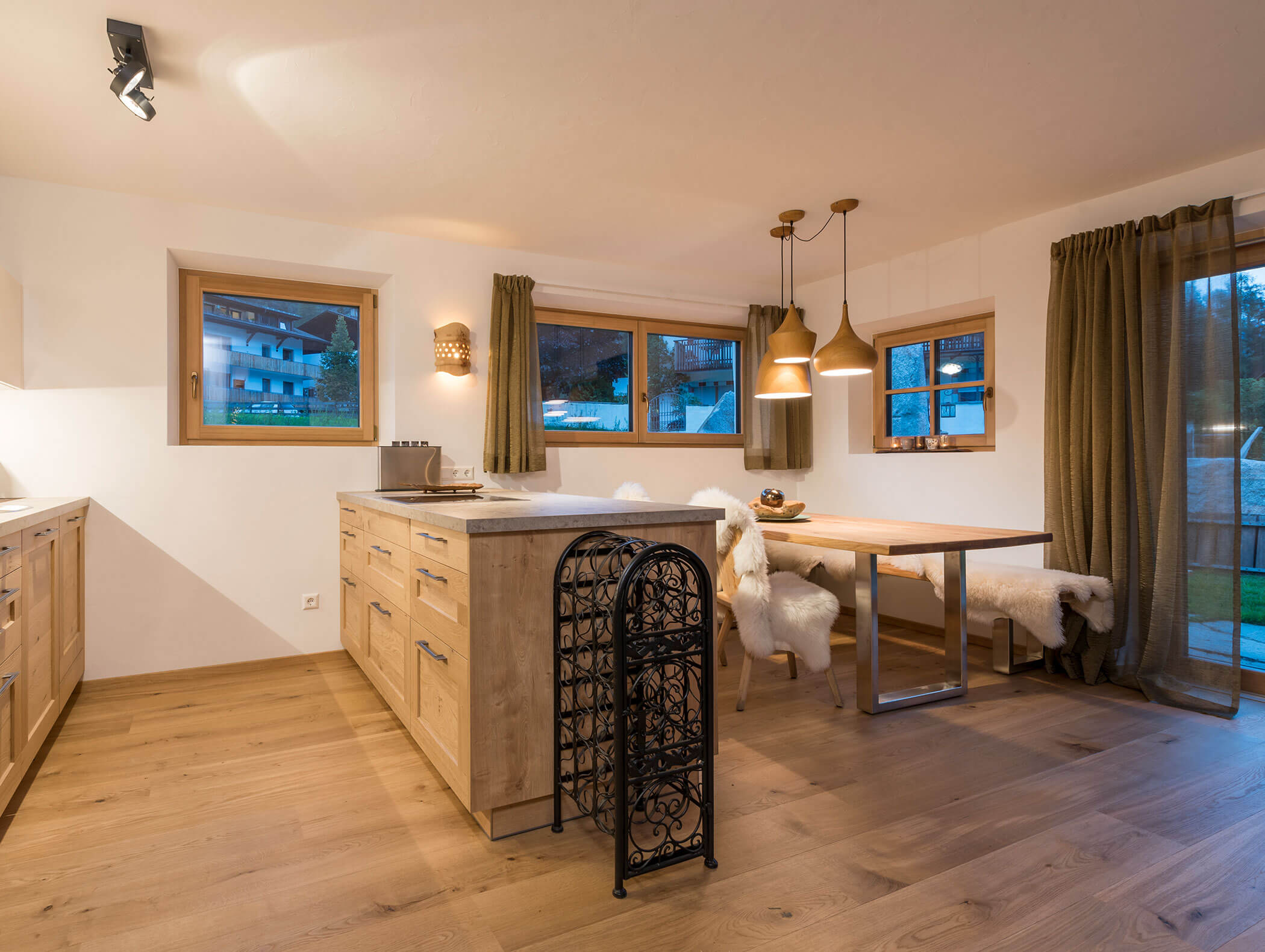 Moderne Küche und Essbereich mit Holzböden, großen Fenstern und gemütlichen Sitzgelegenheiten mit Fellüberwürfen. - Maurlechnhof