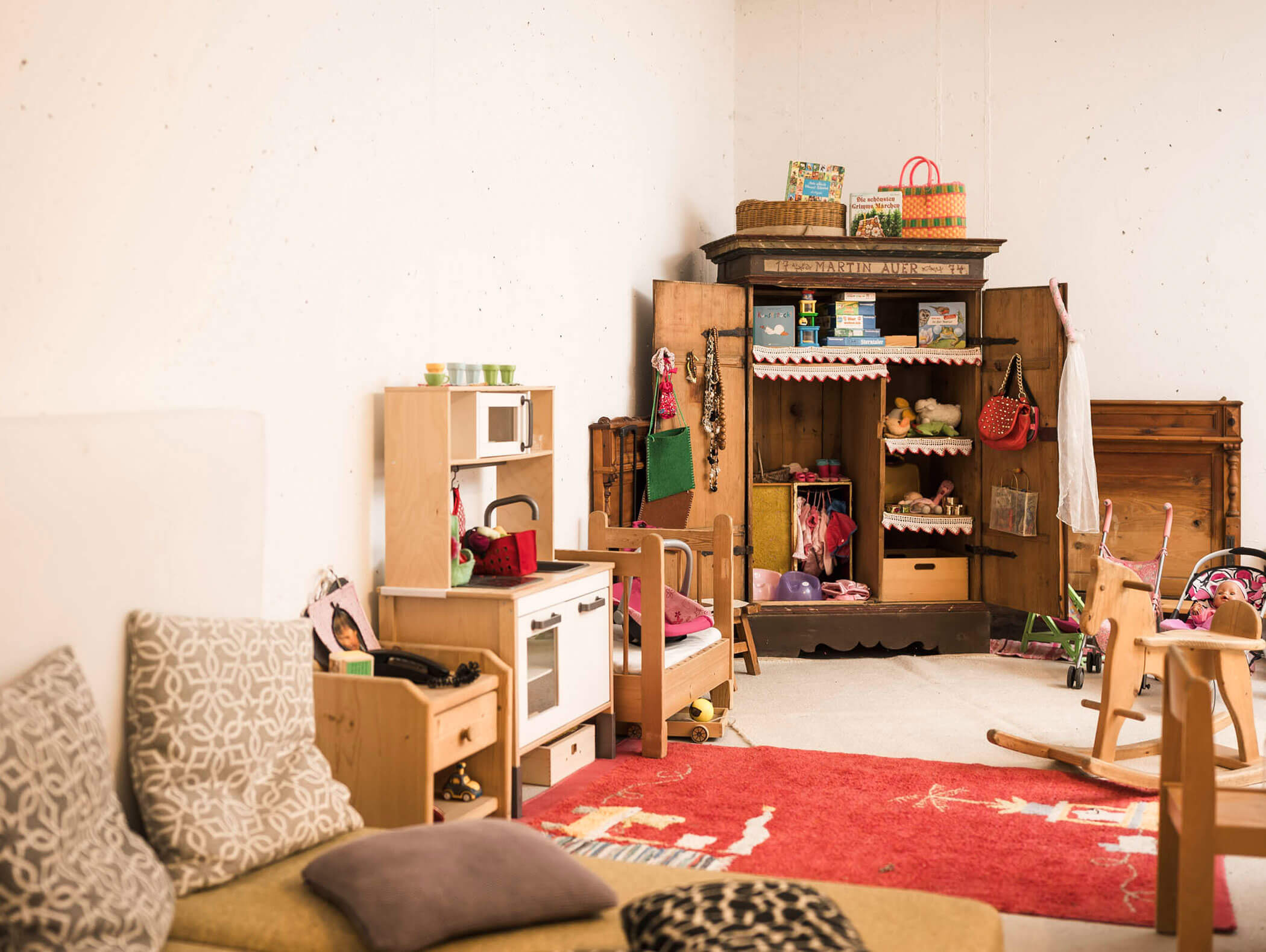 Gemütliches Spielzimmer mit Spielzeugküche, Regalen und Garderobe, gefüllt mit verschiedenen Spielzeugen und Kindersachen. - Maurlechnhof