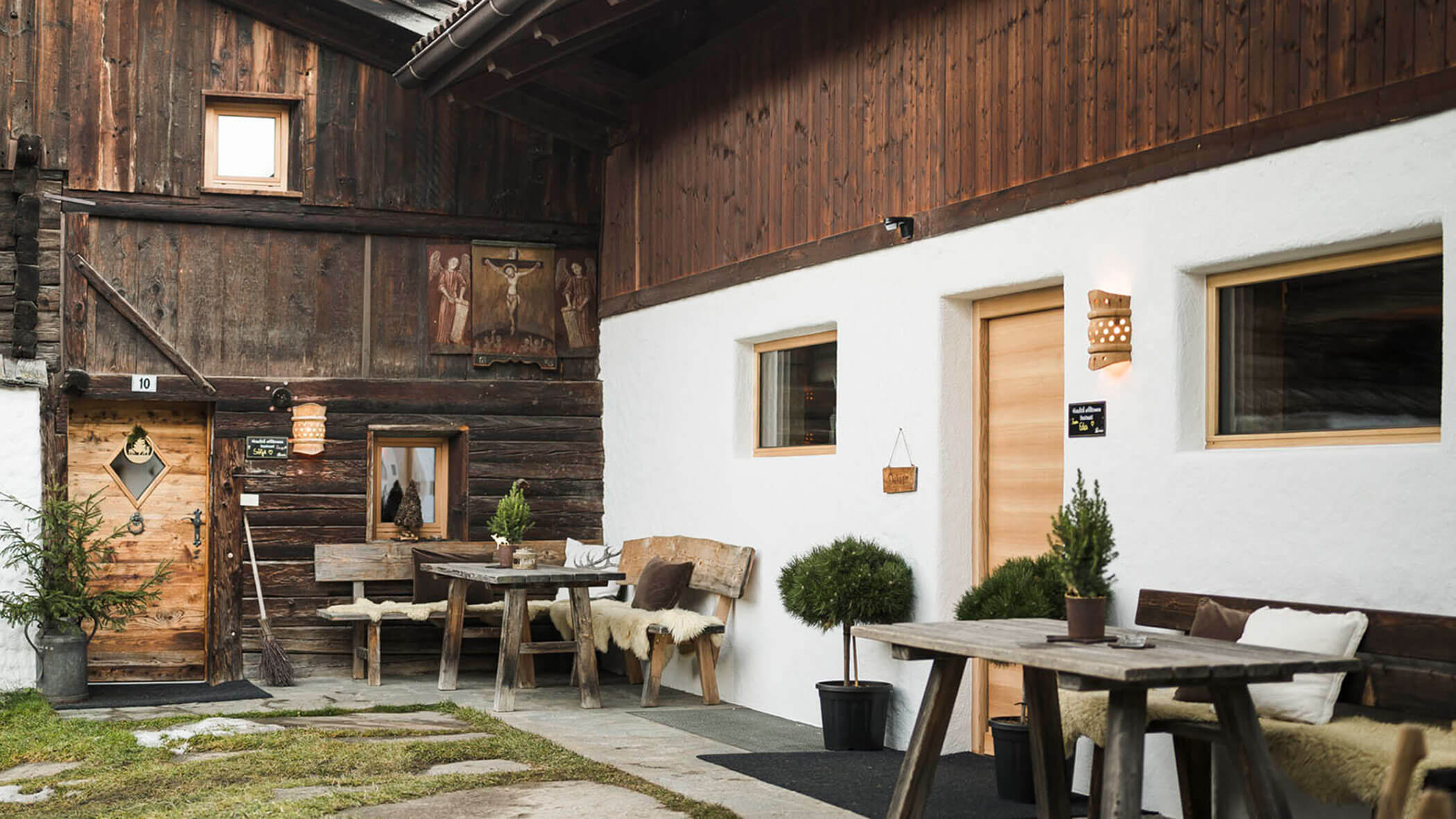 Eine rustikale Holzhütte mit Bänken, Topfpflanzen und gemütlichen Sitzgelegenheiten im Freien. - Maurlechnhof