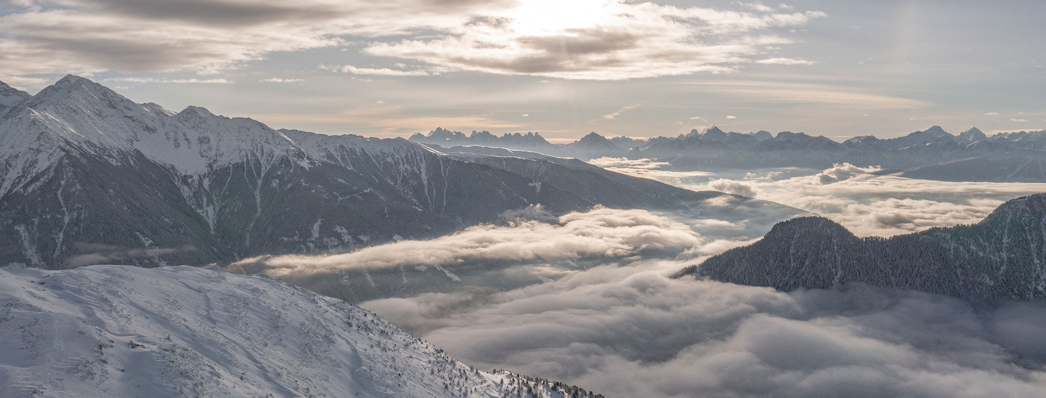 Schneebedeckte Berge und Täler unter einem teilweise bewölkten Himmel bei Sonnenaufgang oder Sonnenuntergang. - Maurlechnhof
